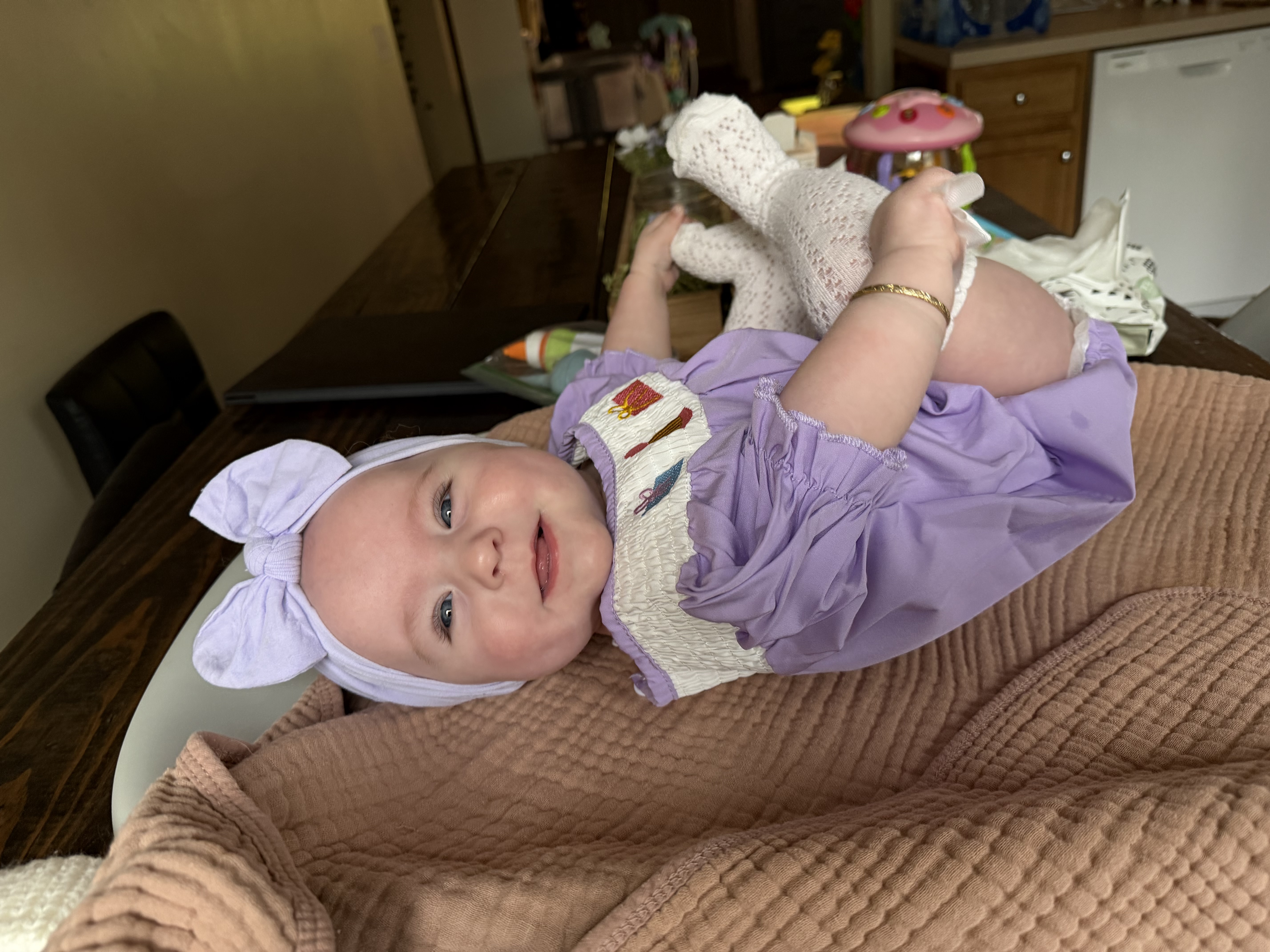 Baby Delilah relaxing in her purple outfit on the couch